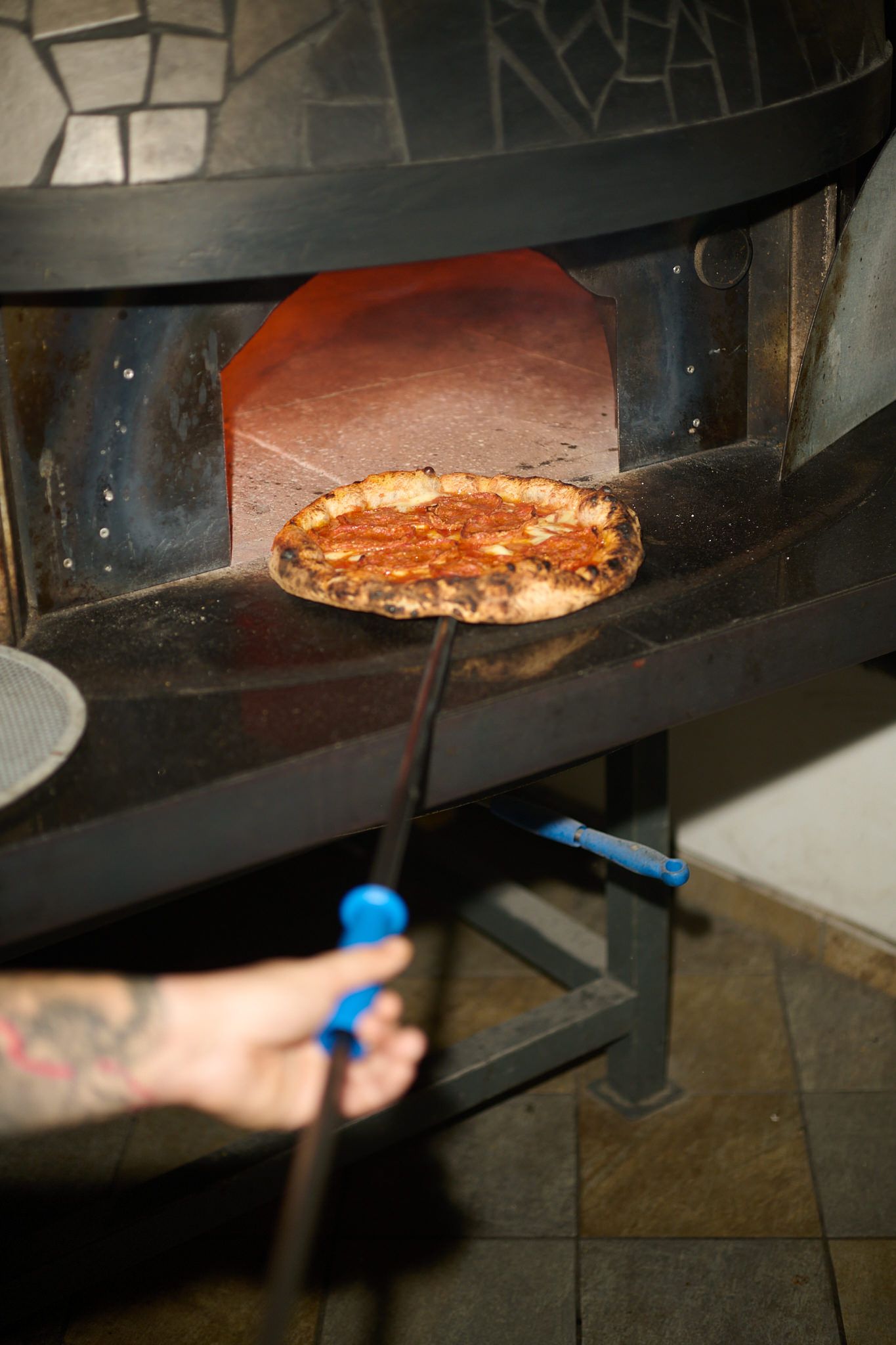 Una pizza entra nel forno rivestito di mosaico