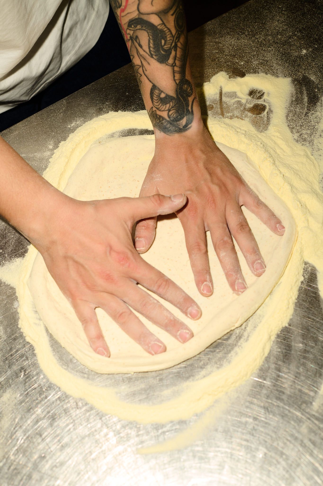 Mani che stendono l’impasto sulla semola